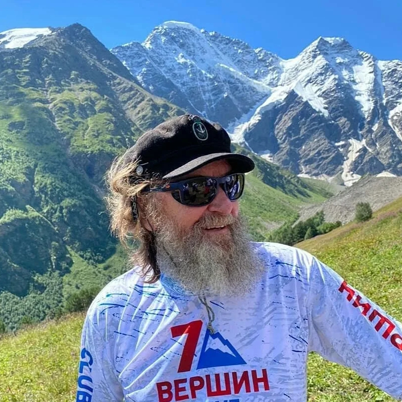 Путишественник Федор Конюхов на фоне гор в темных очках.