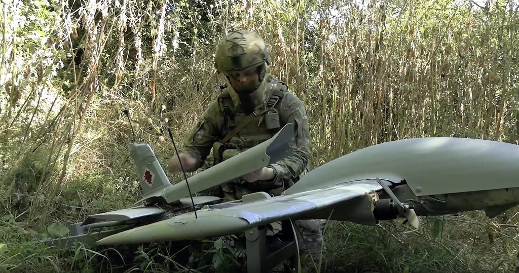 Дрон "Молния-2" в траве и российский военнослужащий.